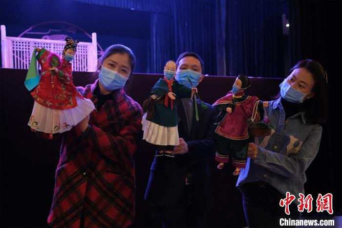 戴上口罩的晋江市掌中木偶剧团演员和木偶合影。　颜英婷 摄