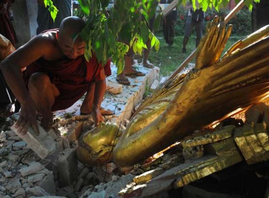 当地时间2012年11月12日，缅甸Sintgu，一名僧人试图保护在地震中倒下的佛像。