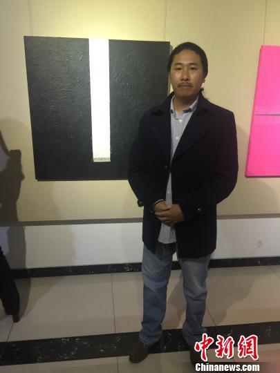 图为蒙古族青年艺术家青龙与他最近创作的作品合影。　乌瑶 摄