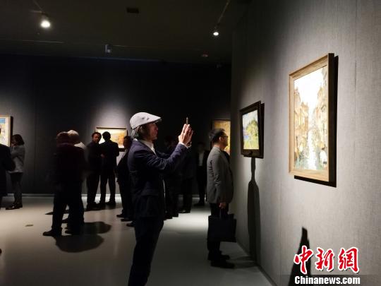 图为，在“印象山东——俄罗斯油画家写生作品展”上，观众在喜欢的作品前驻足观赏、拍照。　孙宏瑗 摄